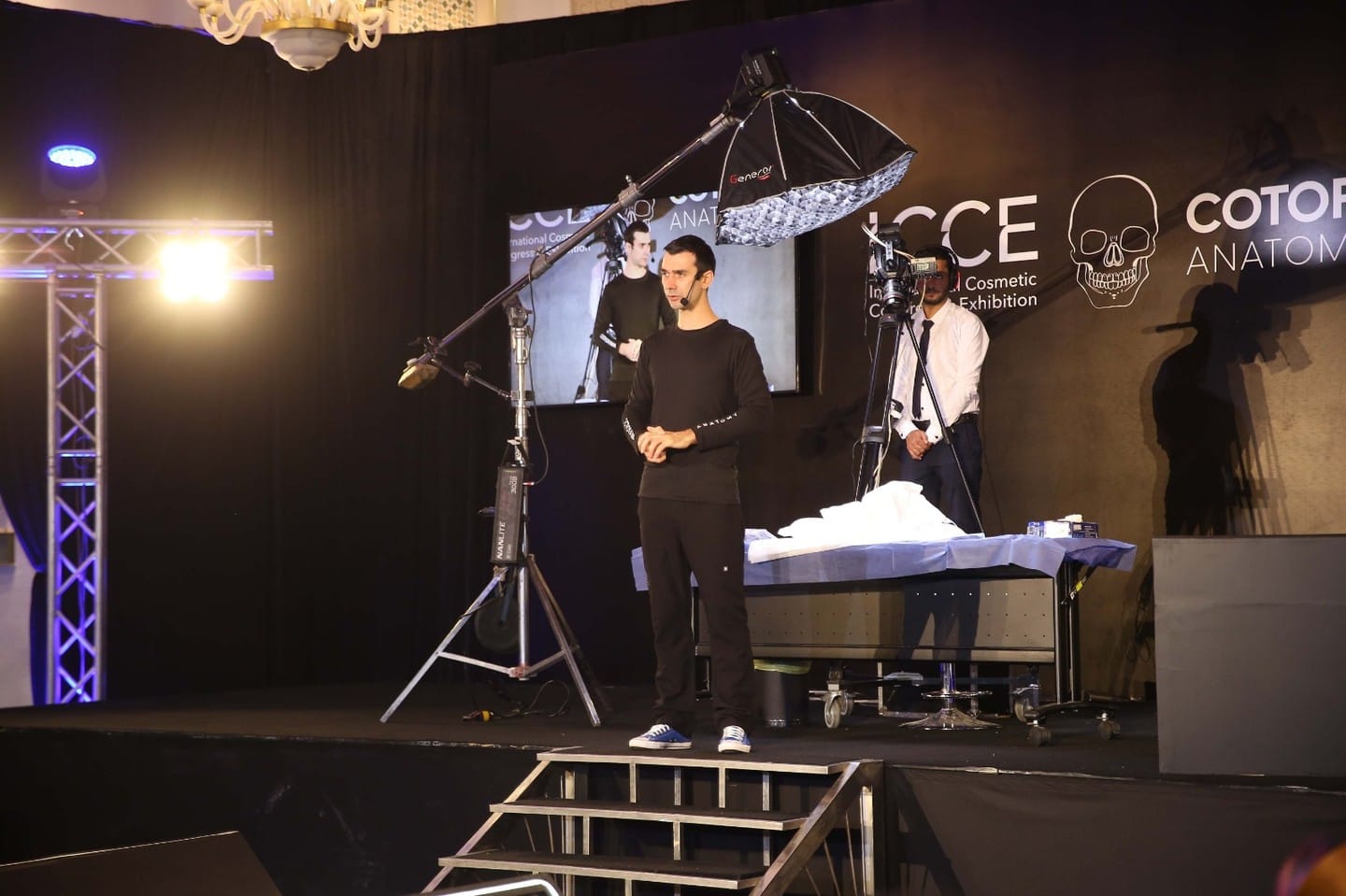 Prof. Sebastian Cotofana on stage with a dissection table and broadcast cameras, ICCE and Cotofana Anatomy backdrop behind